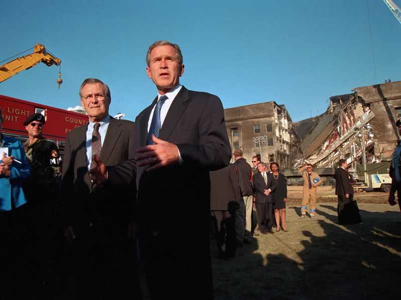 El presidente George W. Bush pronuncia un discurso frente al Pentágono dañado tras el ataque terrorista del 11 de septiembre allí, mientras el consejero del presidente Karen Hughes y el secretario de Defensa Donald Rumsfeld están a la espera. Colección Smith / Gado / Getty Images